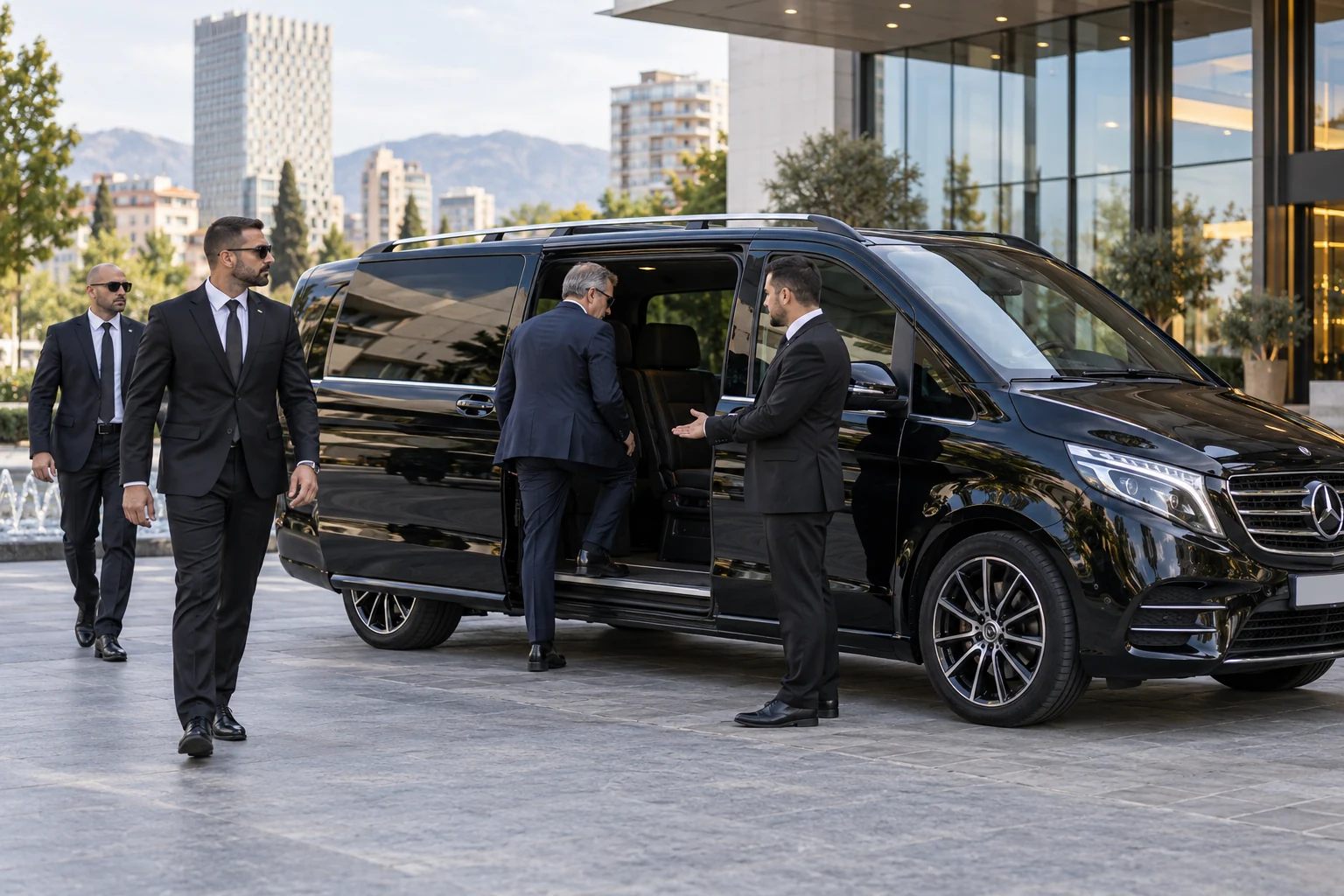 Executive boarding a black premium van with chauffeur and security escorts